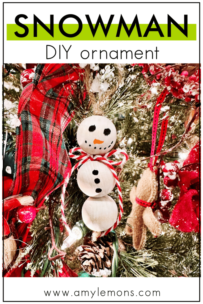 A snowman christmas ornament made by kids hangs on a decorated christmas tree.