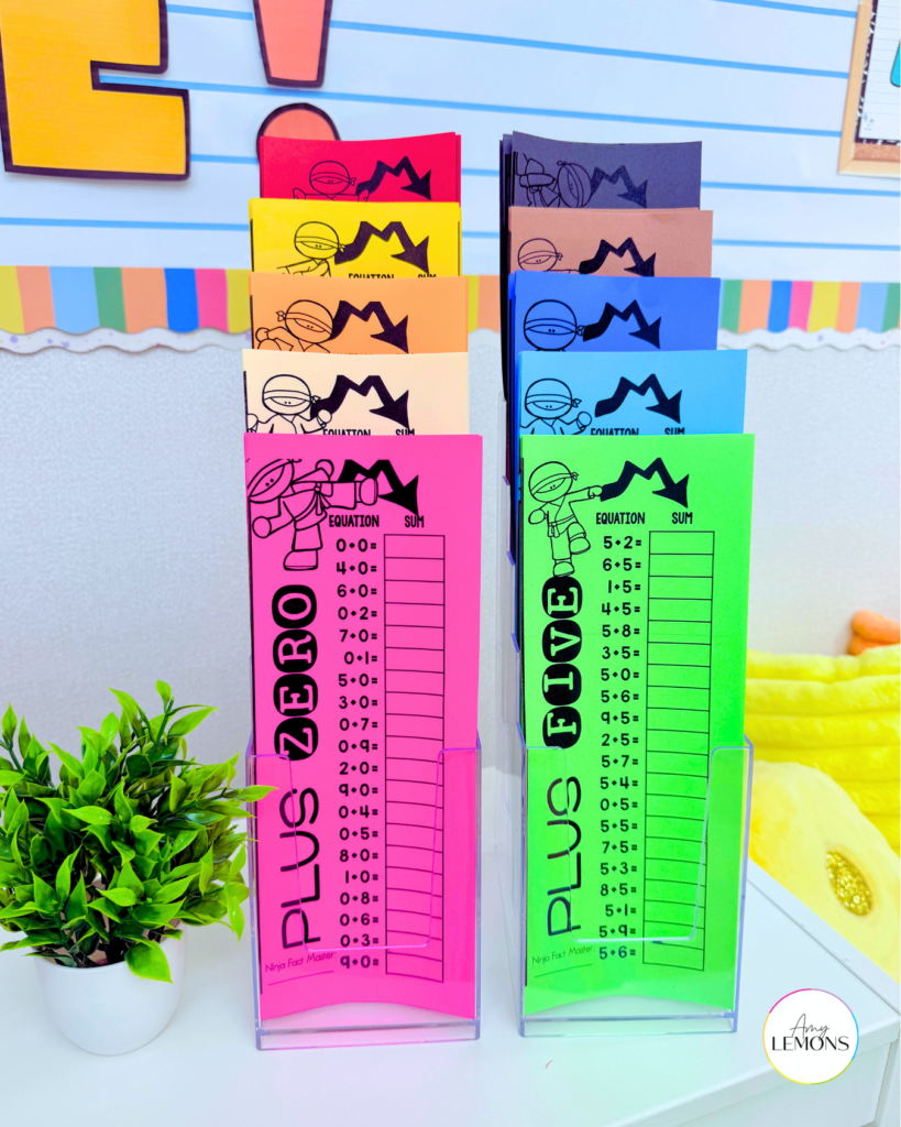 Color-coded addition math fact timed tests in brochure holders next to a Fact Master Ninja tracking folder