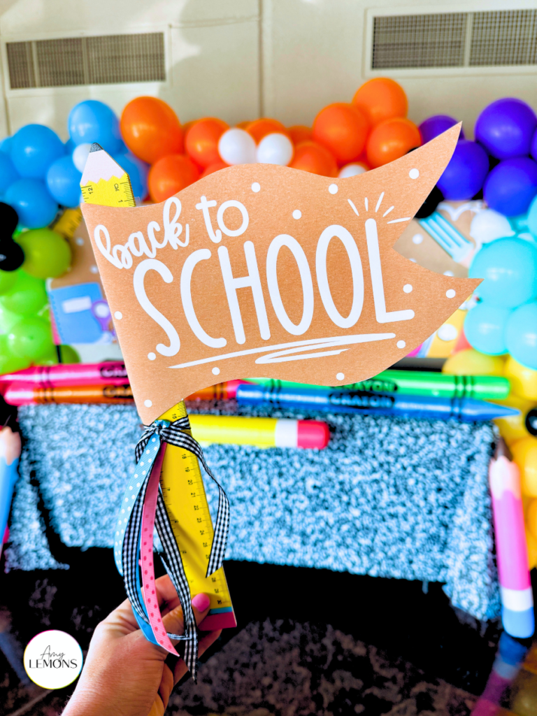 Student holding a back to school pennant sign in front of the photo backdrop